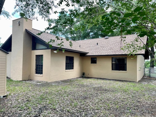 1112 NE 130th Ter, Silver Springs, FL 34488 - rear view of house featuring roof with shingles, stucco siding, and a chimney