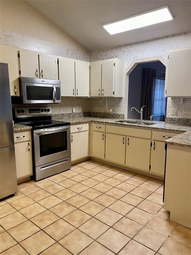 1112 NE 130th Ter, Silver Springs, FL 34488 - kitchen with appliances with stainless steel finishes, backsplash, lofted ceiling, light tile patterned floors, and cream cabinets