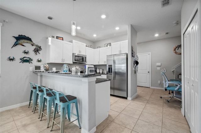14347 Easy Goer St, Ruskin, FL 33573 - kitchen featuring appliances with stainless steel finishes, a kitchen bar, a peninsula, light tile patterned floors, and recessed lighting