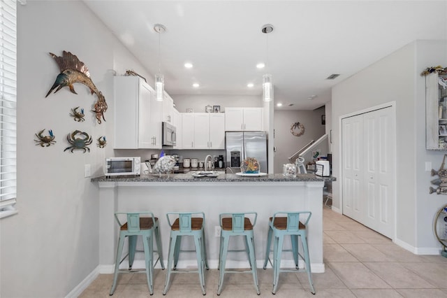 14347 Easy Goer St, Ruskin, FL 33573 - kitchen featuring appliances with stainless steel finishes, a peninsula, a kitchen breakfast bar, white cabinetry, and light tile patterned floors