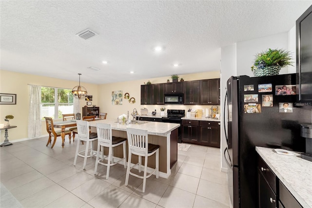 2552 NE 42nd Rd, Ocala, FL 34470 - kitchen with black appliances, a breakfast bar, a textured ceiling, light tile patterned flooring, and a center island with sink