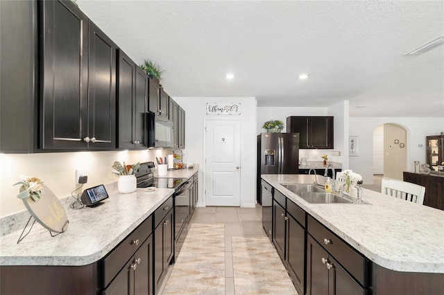 2552 NE 42nd Rd, Ocala, FL 34470 - kitchen with black range with electric cooktop, arched walkways, a center island with sink, light countertops, and light tile patterned flooring