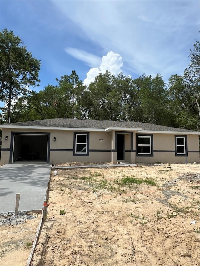10375 SE 126th Ln, Belleview, FL 34420 - view of front of property featuring a garage, stucco siding, and view of wooded area