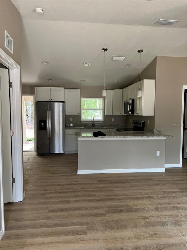 10375 SE 126th Ln, Belleview, FL 34420 - kitchen with stainless steel appliances, white cabinets, wood finished floors, recessed lighting, and vaulted ceiling