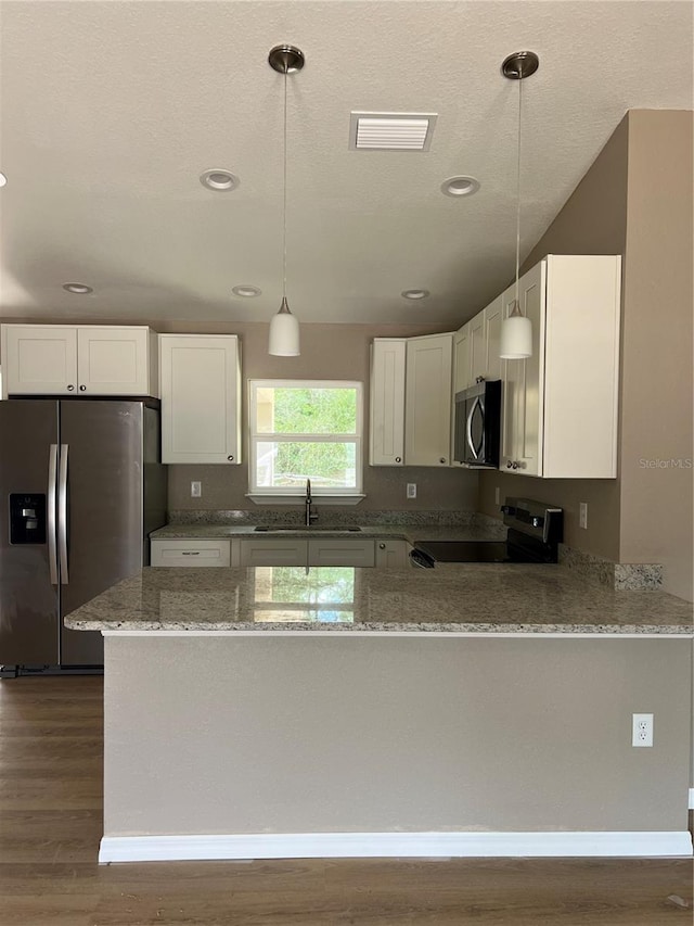 10375 SE 126th Ln, Belleview, FL 34420 - kitchen featuring appliances with stainless steel finishes, light stone counters, dark wood-style floors, a peninsula, and recessed lighting