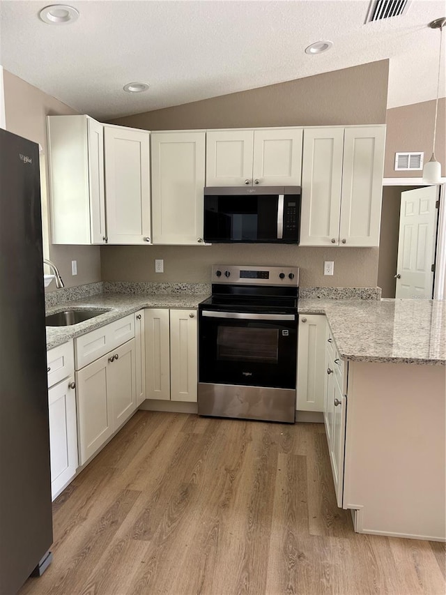 10375 SE 126th Ln, Belleview, FL 34420 - kitchen featuring stainless steel appliances, white cabinetry, lofted ceiling, light wood-style flooring, and light stone countertops