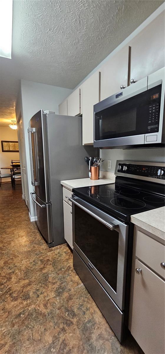 5591 NW 61st Ln, Ocala, FL 34482 - kitchen with appliances with stainless steel finishes, white cabinets, light countertops, and a textured ceiling