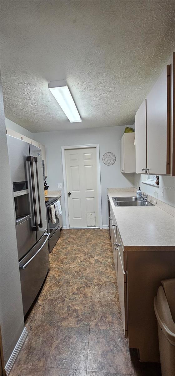 5591 NW 61st Ln, Ocala, FL 34482 - kitchen with electric range, high end fridge, light countertops, a textured ceiling, and dark brown cabinets