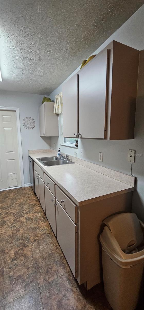 5591 NW 61st Ln, Ocala, FL 34482 - kitchen featuring a textured ceiling, light countertops, dark stone finish flooring, and dishwasher