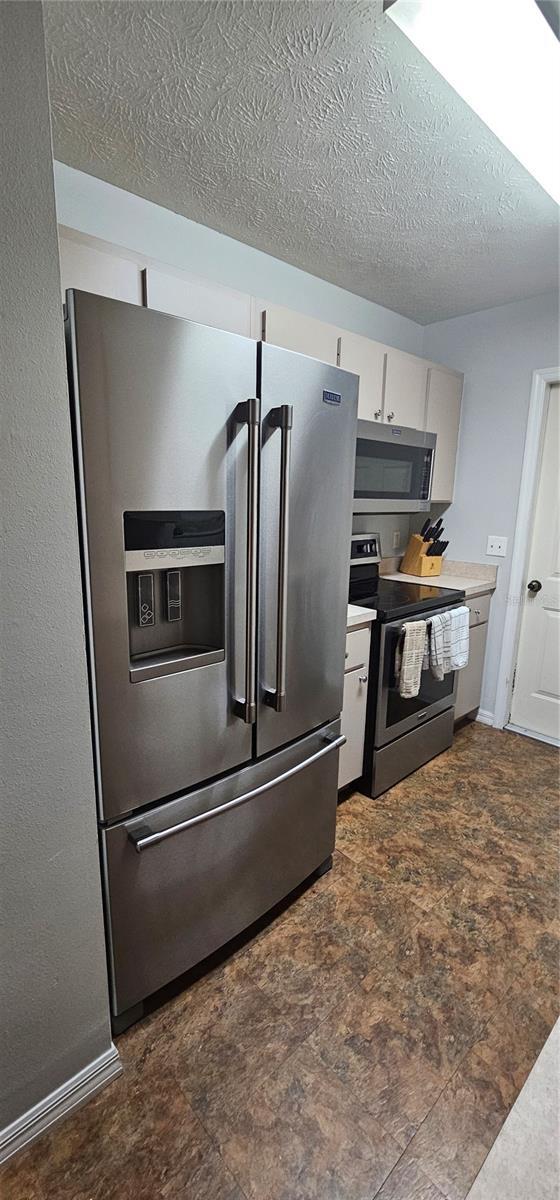 5591 NW 61st Ln, Ocala, FL 34482 - kitchen featuring stainless steel appliances, white cabinets, a textured ceiling, and light countertops