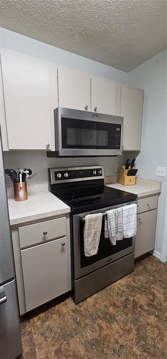 5591 NW 61st Ln, Ocala, FL 34482 - kitchen featuring stainless steel appliances, light countertops, stone finish flooring, and a textured ceiling
