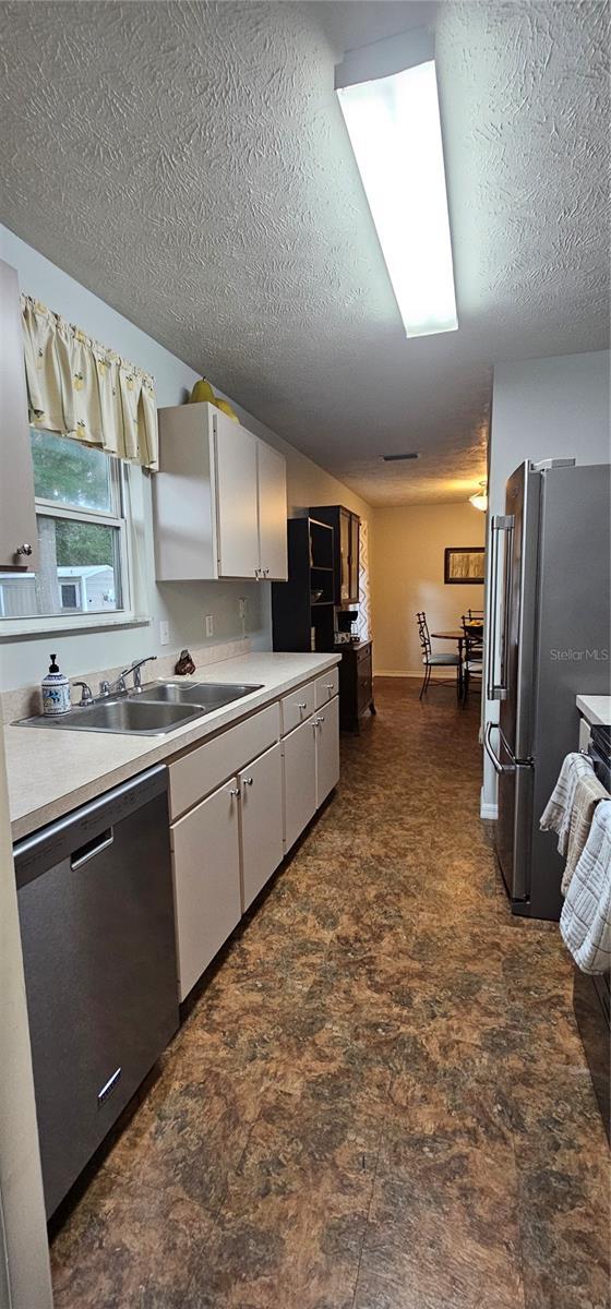5591 NW 61st Ln, Ocala, FL 34482 - kitchen featuring appliances with stainless steel finishes, a textured ceiling, light countertops, and white cabinets