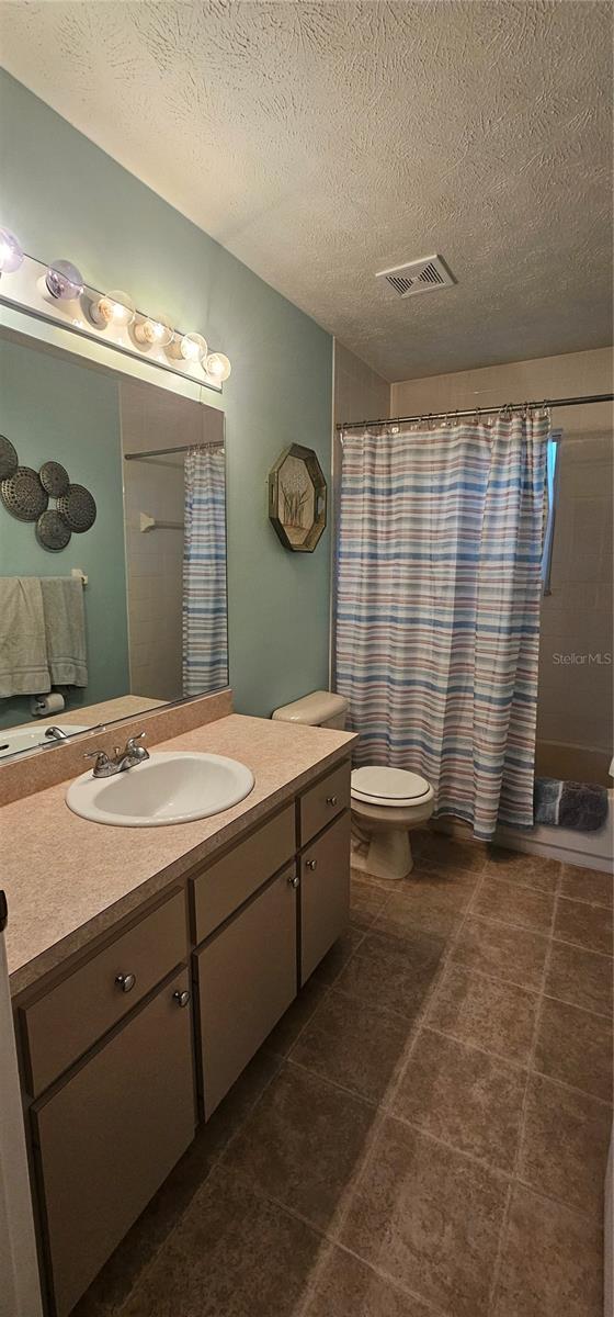 5591 NW 61st Ln, Ocala, FL 34482 - bathroom featuring vanity, a textured ceiling, tile patterned floors, and curtained shower