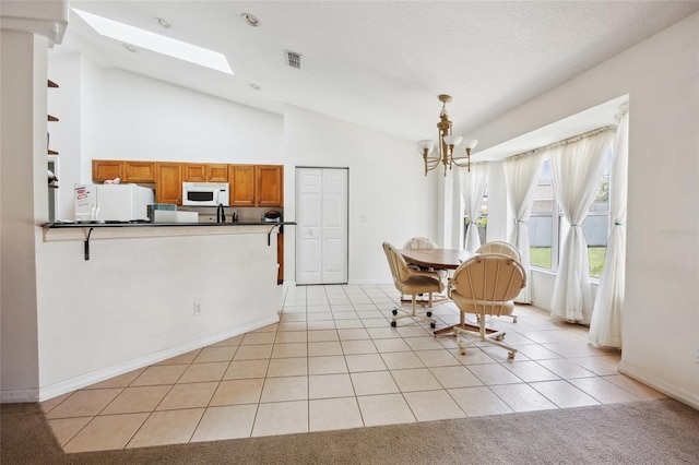 4300 NW 4th Cir, Ocala, FL 34475 - dining space featuring lofted ceiling, a chandelier, a skylight, and light tile patterned floors
