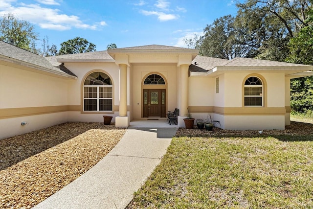 4322 N Mayan Dr, Hernando, FL 34442 - view of exterior entry featuring roof with shingles, stucco siding, and a lawn