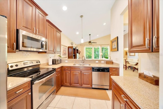 814 Copperhead Cir, Saint Augustine, FL 32092 - kitchen with stainless steel appliances, decorative backsplash, light stone counters, lofted ceiling, and brown cabinetry