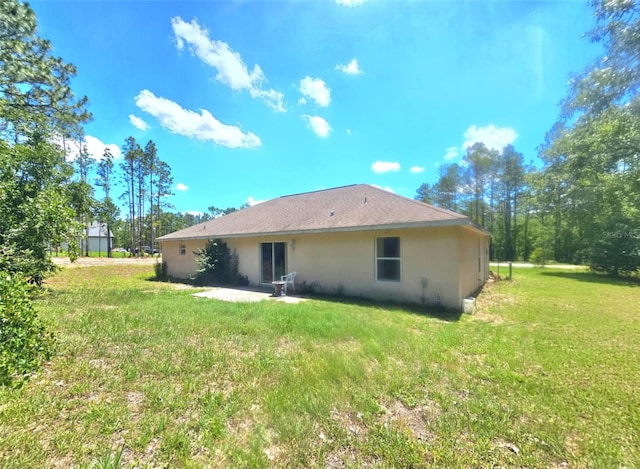 15483 Penn State Rd, Weeki Wachee, FL 34614 - rear view of property featuring a lawn, stucco siding, and a patio