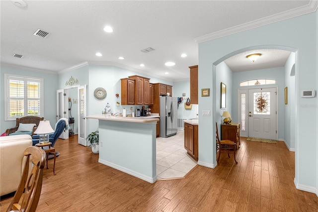 8566 SW 83rd Loop, Ocala, FL 34481 - kitchen featuring stainless steel fridge, arched walkways, light countertops, light wood-style flooring, and brown cabinetry