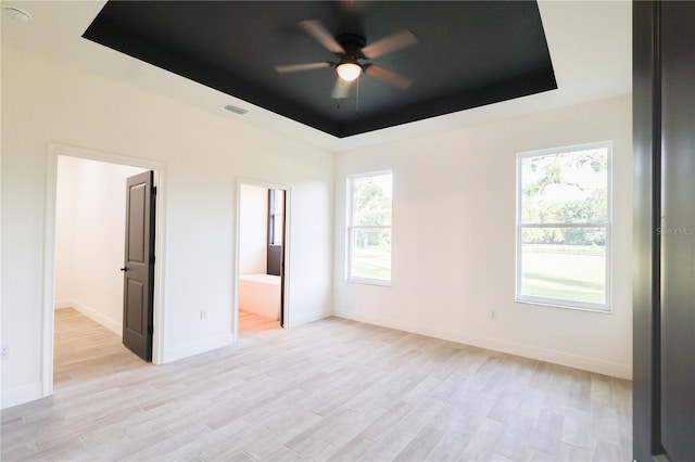 7 Hill Prince Dr, Ocala, FL 34482 - unfurnished bedroom with a tray ceiling, light wood-style floors, and ensuite bathroom