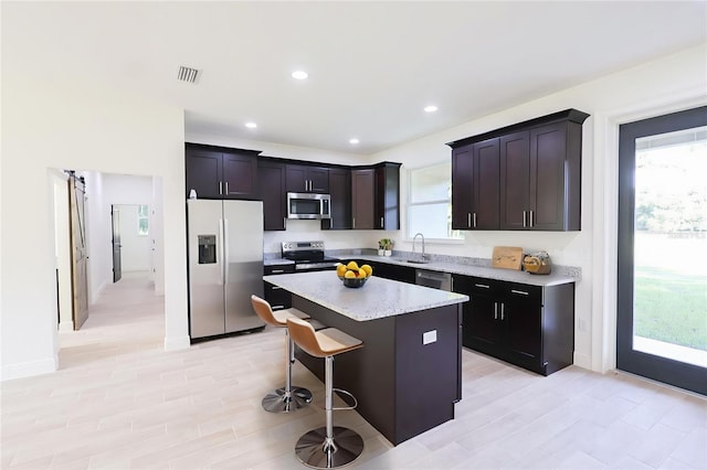 7 Hill Prince Dr, Ocala, FL 34482 - kitchen with appliances with stainless steel finishes, a kitchen island, a breakfast bar, recessed lighting, and light stone countertops