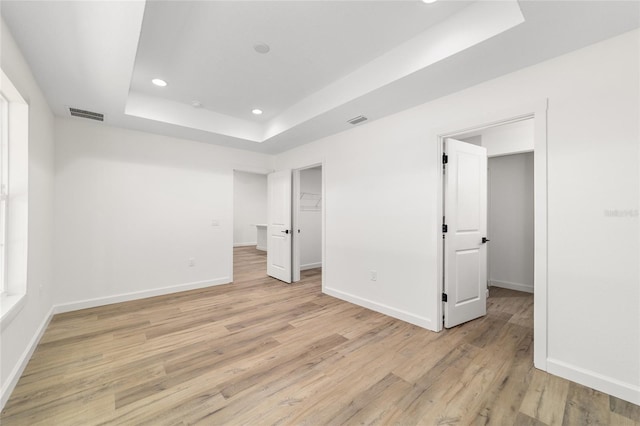 5400 NW 9th St, Ocala, FL 34482 - unfurnished bedroom featuring a tray ceiling, light wood-type flooring, recessed lighting, and a walk in closet