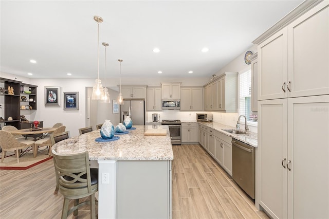 4340 NW 56th Ct, Ocala, FL 34482 - kitchen with stainless steel appliances, a kitchen bar, a kitchen island, light wood-style floors, and light stone counters
