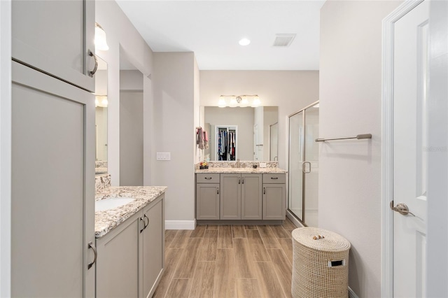 4340 NW 56th Ct, Ocala, FL 34482 - bathroom featuring wood finished floors, two vanities, a stall shower, and a spacious closet