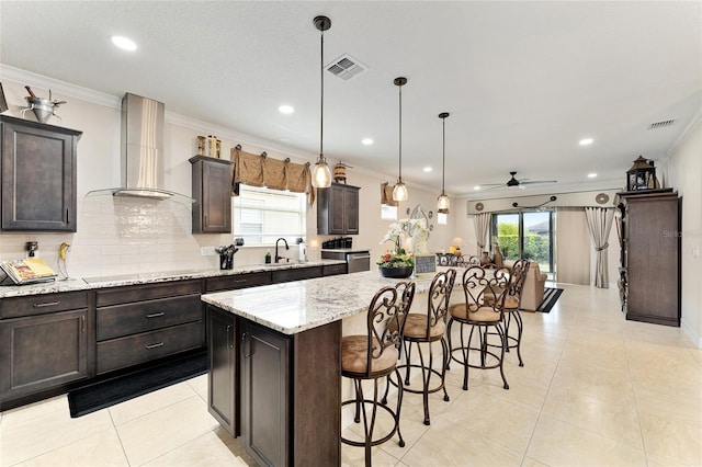 9634 SW 67th St, Ocala, FL 34481 - kitchen featuring wall chimney exhaust hood, a kitchen bar, a center island, crown molding, and ceiling fan