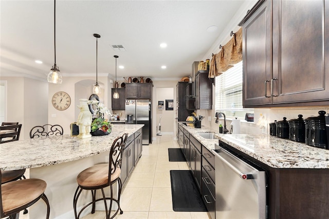 9634 SW 67th St, Ocala, FL 34481 - kitchen with stainless steel appliances, a breakfast bar, light tile patterned flooring, dark brown cabinetry, and ornamental molding