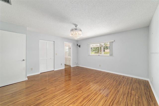 8881 SW 94th St Unit E, Ocala, FL 34481 - unfurnished bedroom featuring a chandelier, wood finished floors, a textured ceiling, a closet, and ensuite bath