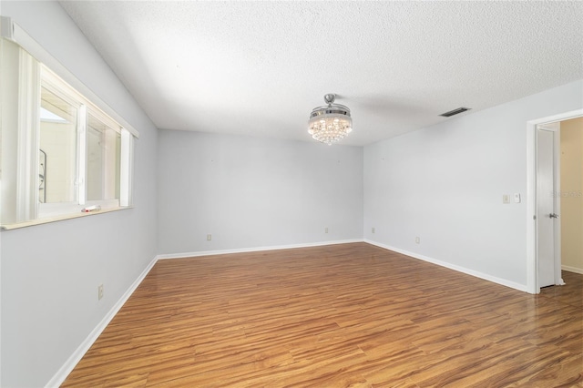 8881 SW 94th St Unit E, Ocala, FL 34481 - spare room featuring wood finished floors, a textured ceiling, and a chandelier