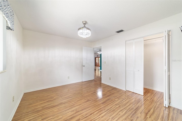 8881 SW 94th St Unit E, Ocala, FL 34481 - unfurnished bedroom with light wood-style flooring, a chandelier, and a closet