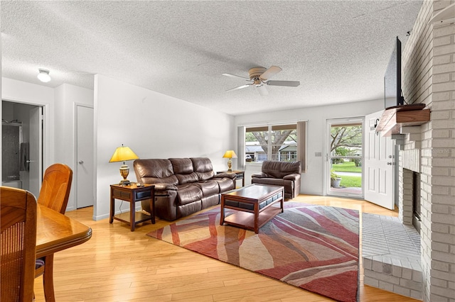 8850 SW 97th St Unit C, Ocala, FL 34481 - living room featuring a ceiling fan, light wood-type flooring, a textured ceiling, and a fireplace