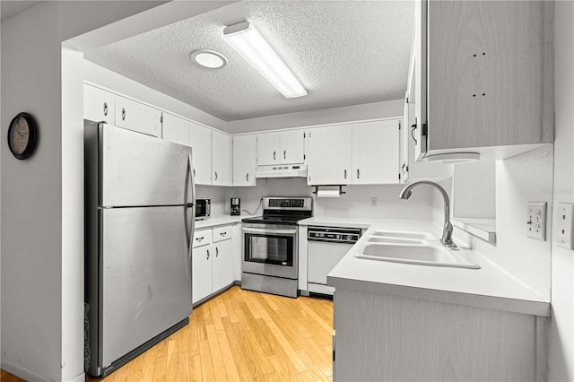 8850 SW 97th St Unit C, Ocala, FL 34481 - kitchen with appliances with stainless steel finishes, a textured ceiling, under cabinet range hood, light wood-style flooring, and light countertops