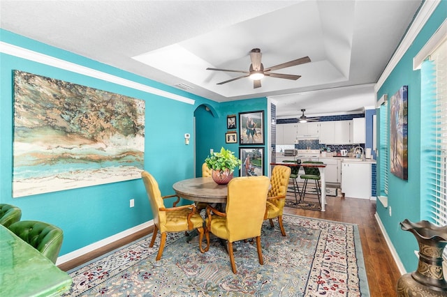 7242 SW 115th Pl, Ocala, FL 34476 - dining space featuring a tray ceiling, dark wood-style floors, a ceiling fan, and arched walkways