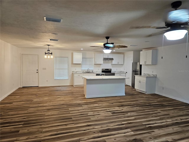 51 NE 10th St, Williston, FL 32696 - kitchen with electric range oven, a ceiling fan, dark wood finished floors, and white cabinetry