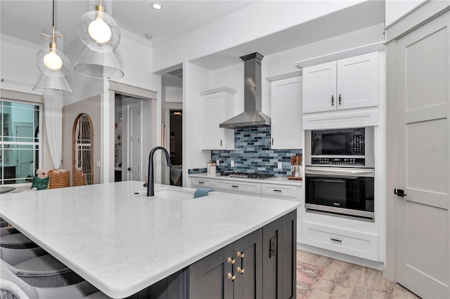 3196 W Mustang Blvd, Beverly Hills, FL 34465 - kitchen with appliances with stainless steel finishes, wall chimney range hood, ornamental molding, white cabinets, and a center island with sink