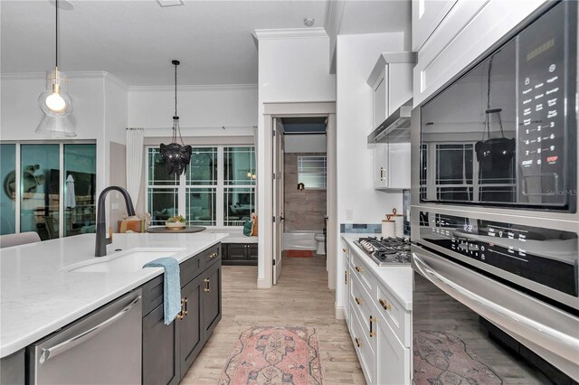 3196 W Mustang Blvd, Beverly Hills, FL 34465 - kitchen featuring appliances with stainless steel finishes, white cabinets, hanging light fixtures, light wood finished floors, and crown molding
