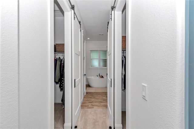 3196 W Mustang Blvd, Beverly Hills, FL 34465 - hall featuring a barn door, a textured wall, light colored carpet, and light wood-style floors
