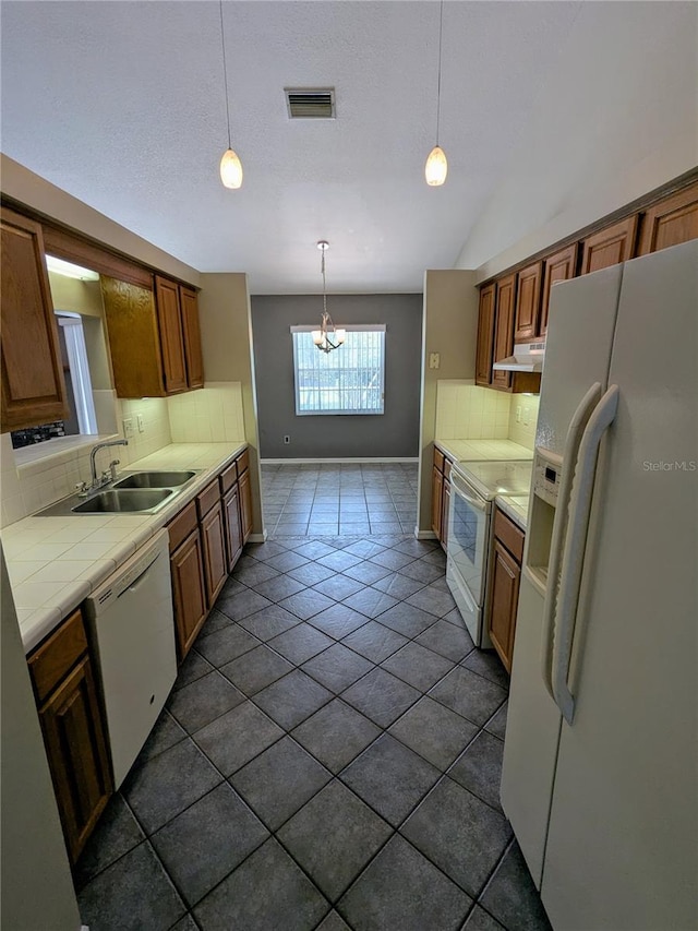 3650 SE 55th Ct, Ocala, FL 34480 - kitchen featuring white appliances, under cabinet range hood, tile counters, backsplash, and a chandelier