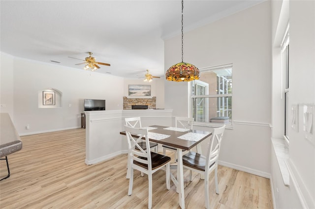 7220 NW 83rd Ter, Ocala, FL 34482 - dining area featuring crown molding, a stone fireplace, a ceiling fan, and light wood-style flooring