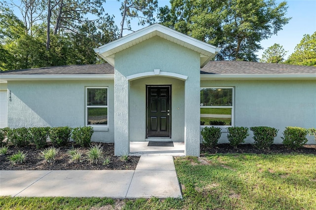 5740 NW 61st St, Ocala, FL 34482 - property entrance featuring stucco siding, roof with shingles, and a yard