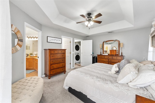 6362 N Walter Ter, Citrus Springs, FL 34434 - bedroom with stacked washer / dryer, a raised ceiling, light carpet, connected bathroom, and ceiling fan