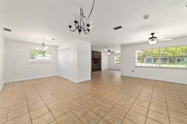 5500 SE 2nd Pl, Ocala, FL 34480 - unfurnished living room featuring a chandelier, ceiling fan, light tile patterned floors, and a stone fireplace