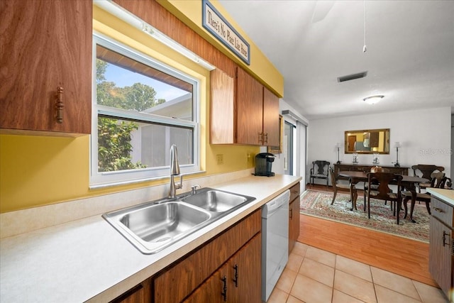 5525 NE 22nd Ave, Ocala, FL 34479 - kitchen with white dishwasher, light countertops, light tile patterned flooring, and brown cabinets