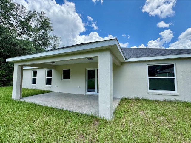 13305 SW 114th Pl, Dunnellon, FL 34432 - rear view of property featuring a patio, a lawn, stucco siding, and a shingled roof