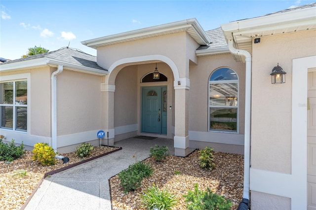 7243 SE 172nd Legacy Ln, The Villages, FL 32162 - doorway to property with stucco siding and a shingled roof