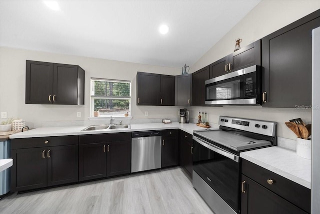 13479 SW 100th Ln, Dunnellon, FL 34432 - kitchen featuring stainless steel appliances, light countertops, lofted ceiling, light wood-style floors, and dark cabinets