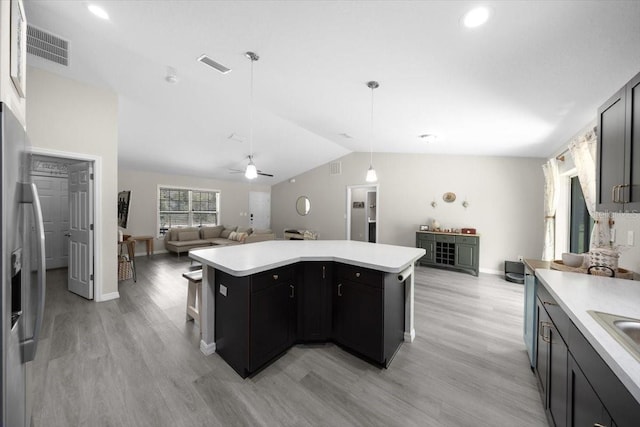 13479 SW 100th Ln, Dunnellon, FL 34432 - kitchen with stainless steel fridge, lofted ceiling, light countertops, open floor plan, and light wood finished floors