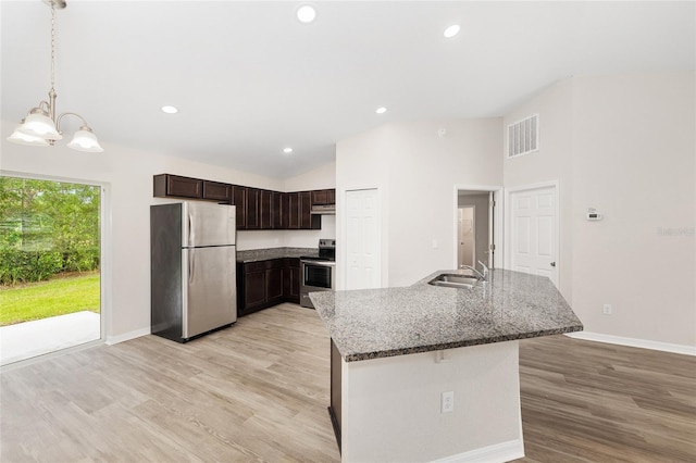 5 Water Pass, Ocala, FL 34472 - kitchen with stainless steel appliances, lofted ceiling, dark brown cabinetry, dark stone counters, and light wood-style flooring